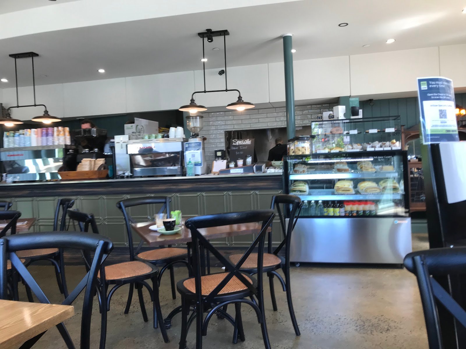 Interior of Artizan Coffee on Liverpool Street, Hobart, showing the sage-green counter, espresso machines, pastry cabinet and dine-in seating