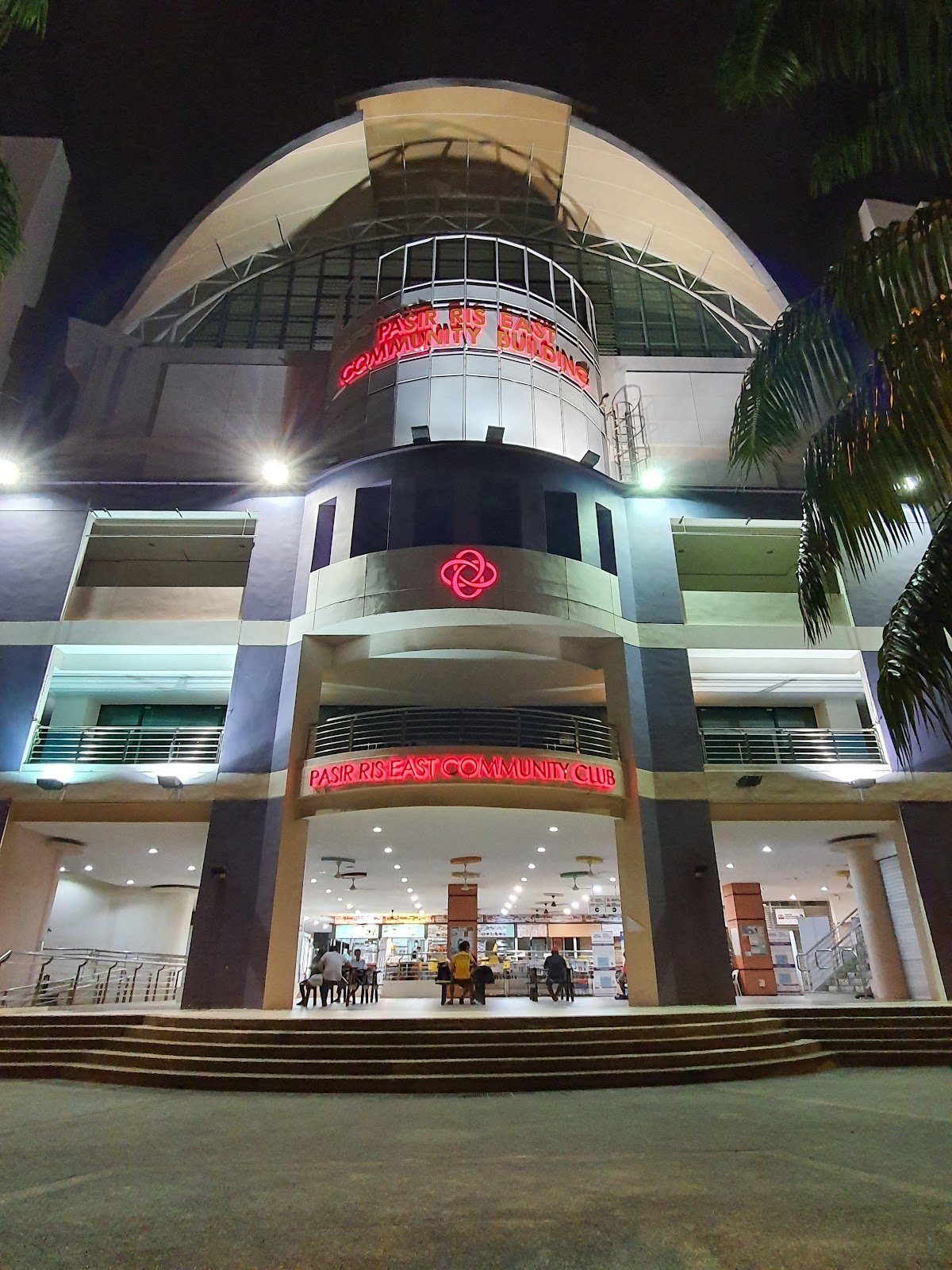 Night exterior of Pasir Ris East Community Club with red neon signage and a lit entrance on Pasir Ris Drive 4