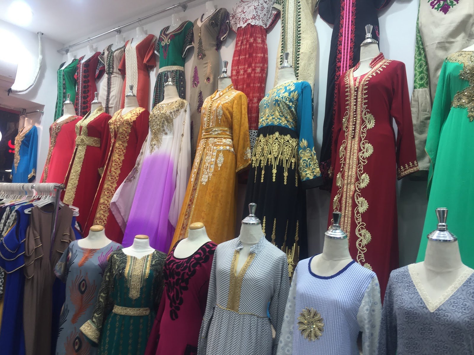 Embroidered abayas and occasion dresses displayed on mannequins in Taiba Market